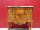 a small chest of drawers on a stand against a red wall