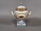 a blue and white vase with a lid on a stand