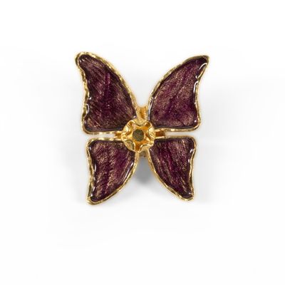 a close up of a purple butterfly broochle on a white background