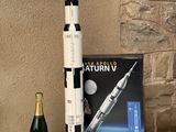 une maquette de la fusée Saturn V et une bouteille de champagne posées sur une table