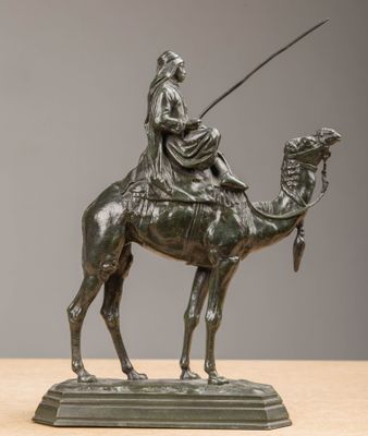 bronze statue of a man riding a camel with a spear in his hand