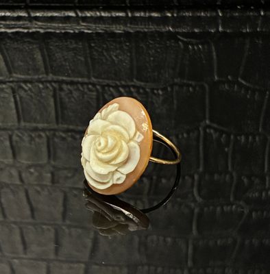 une bague ornée d'une fleur posée sur une surface noire