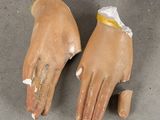 pair of clay hands with a yellow band on them on a gray surface