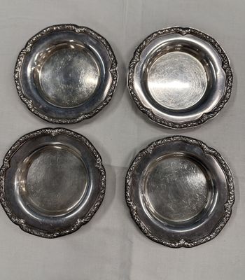 four silver plate dishes on a table with a white background