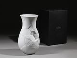 un vase blanc orné d'un motif craquelé, posé à côté d'une boîte noire