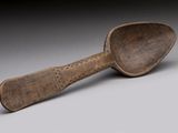 an old wooden spoon sitting on top of a gray surface