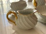 a white and gold tea set on a white table