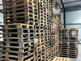 des palettes empilées dans un entrepôt, avec une fourche au premier plan