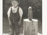 a black and white photo of a young boy standing next to a statue