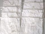 Plusieurs chemises blanches sont emballées dans des sacs en plastique sur une table