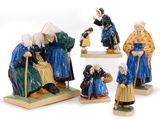 three figurines of people sitting on a table with one holding a child