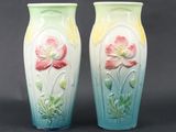 two vases with flowers painted on them sitting on a table