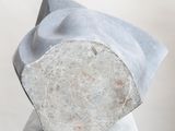 concrete sculpture of a rock on a white pedestal with a white background