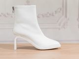 un gros plan sur une paire de bottines blanches posées sur un parquet