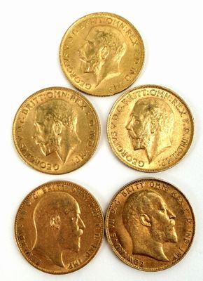 quatre types différents de pièces d'or sont présentés sur une surface blanche