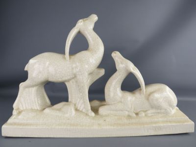 a white sculpture of a bird and a bird on a rock