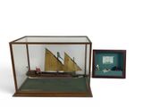 an old model of a ship in a glass case next to a framed picture
