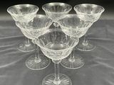 six clear wine glasses sitting on top of a table next to each other