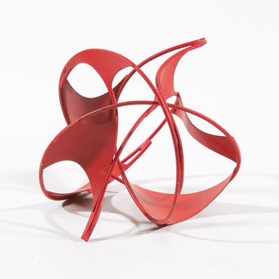 une sculpture rouge sur une surface blanche, avec un fond blanc
