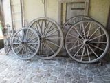 trois vieilles roues de wagon en bois adossées à un mur
