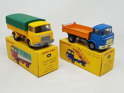 deux camions miniatures posés sur des cartons, sur une surface blanche