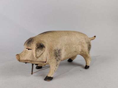 un petit cochon en peluche posé sur une surface blanche