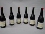 six bottles of wine are lined up in a row on a table