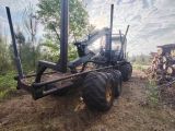a tractor that is parked next to a pile of logs