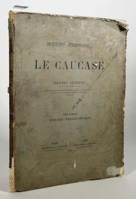 un vieux livre posé sur une table à côté d'un mur blanc