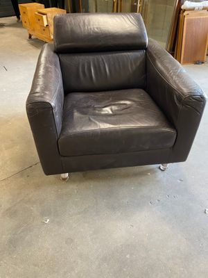 black leather chair in a warehouse with other furniture in the background
