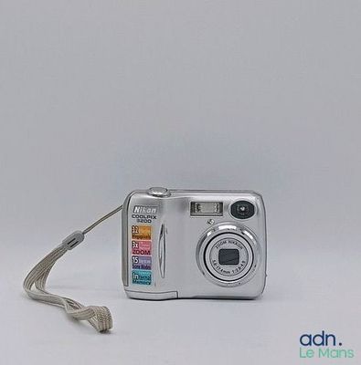 un appareil photo argenté posé sur une surface blanche