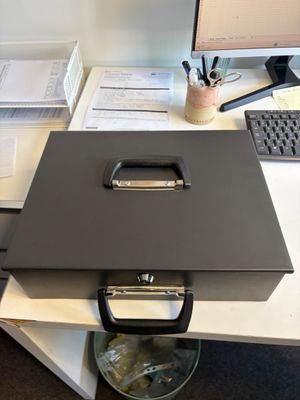 une boîte noire posée sur un bureau, à côté d'un écran d'ordinateur