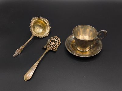 two silver spoons and a cup on a black surface