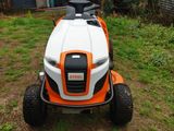 an orange and white lawn mower sitting on top of a grass covered field