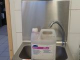 a stainless steel sink with a soap dispenser on the wall