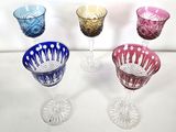 four different colored glass wine glasses sitting on a table