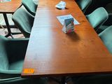 une table en bois avec des chaises vertes et un livre posé dessus