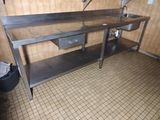 une table en acier inoxydable équipée d'un évier et d'une poubelle