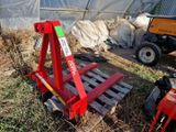 un chariot élévateur rouge garé dans l'herbe, à côté d'un tas de foin