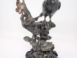 statue représentant un oiseau perché sur une branche, tenant une fleur dans son bec
