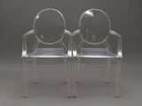 two clear plastic chairs sitting side by side on a gray background