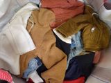 a pile of clothes sitting in a basket on a bed