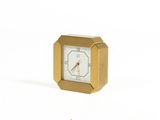 a small gold clock sitting on a white surface
