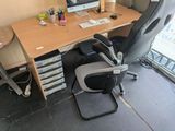 a desk with a computer and a chair in front of a window
