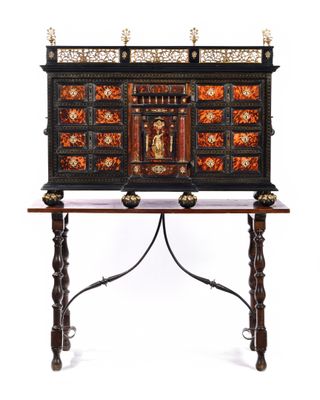 a black and gold painted chest on a stand with a wooden top