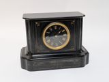 a small black clock with a gold face on a white background