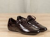 pair of brown shoes on a wooden table with a curtain in the background