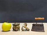 three figurines sitting next to an apple on a table