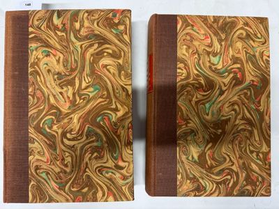 deux livres ornés de motifs dorés et verts, posés sur une surface blanche