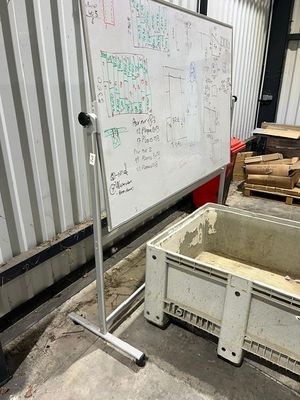 un tableau blanc accroché au mur, à côté d'une caisse en bois
